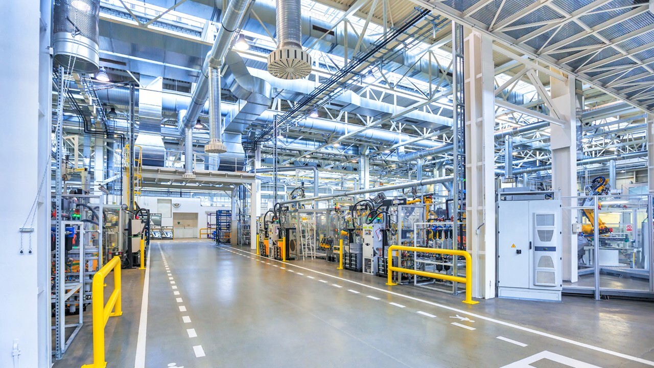 Automated industrial factory floor with robotic arms and IoT sensors.