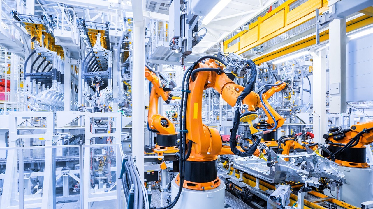 Orange robotic arms operating on an automated production line illustrating Private 5G applications in industrial manufacturing